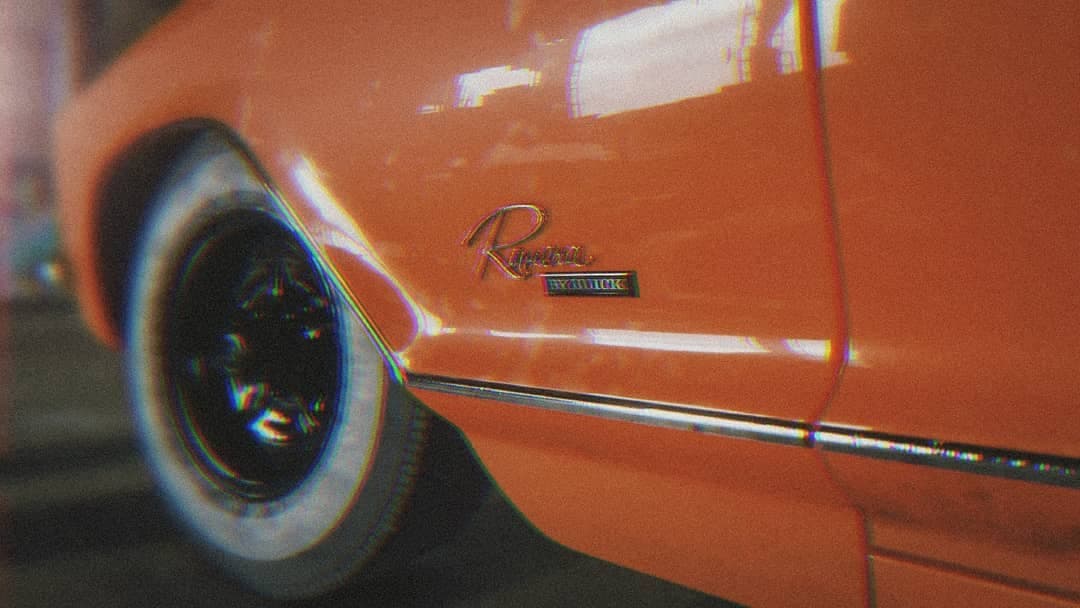 Close crop of a classic orange coupé's wheel arch and chrome trim